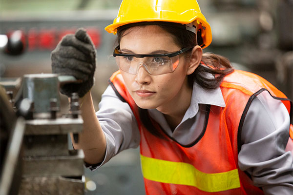 A woman in a hard hat using machinery.